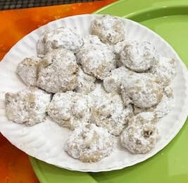 Paper plate of crumbly nut round cookies with confectioner's sugar sifted on top