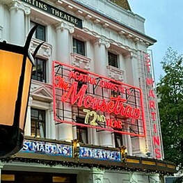 A neon sign on a theater reading Agatha Christie's The Mousetrap 72nd Year