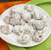 Paper plate of crumbly nut round cookies with confectioner's sugar sifted on top